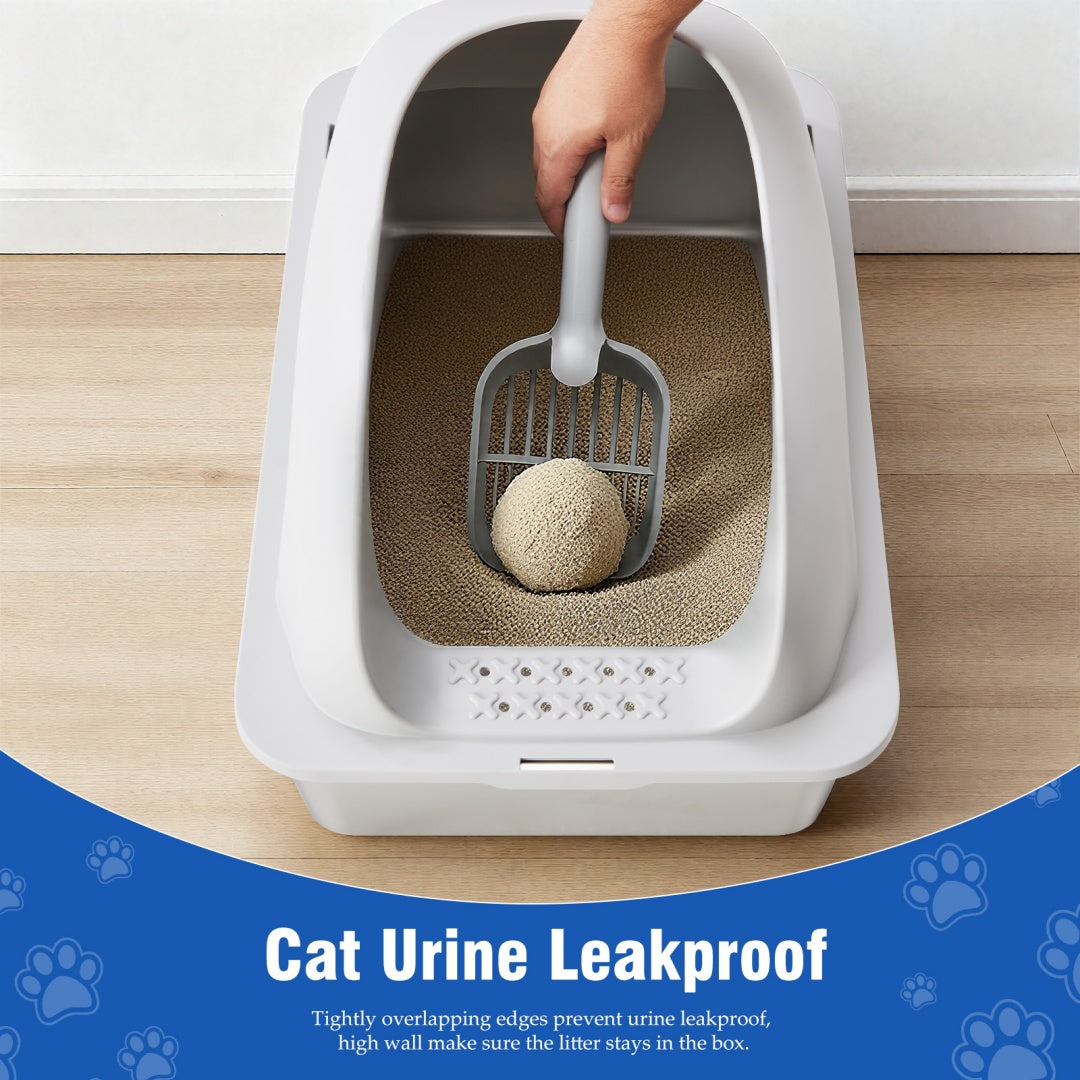 Hand lifting a scoop from the white and steel litter box on a wood floor, showing its high leakproof walls