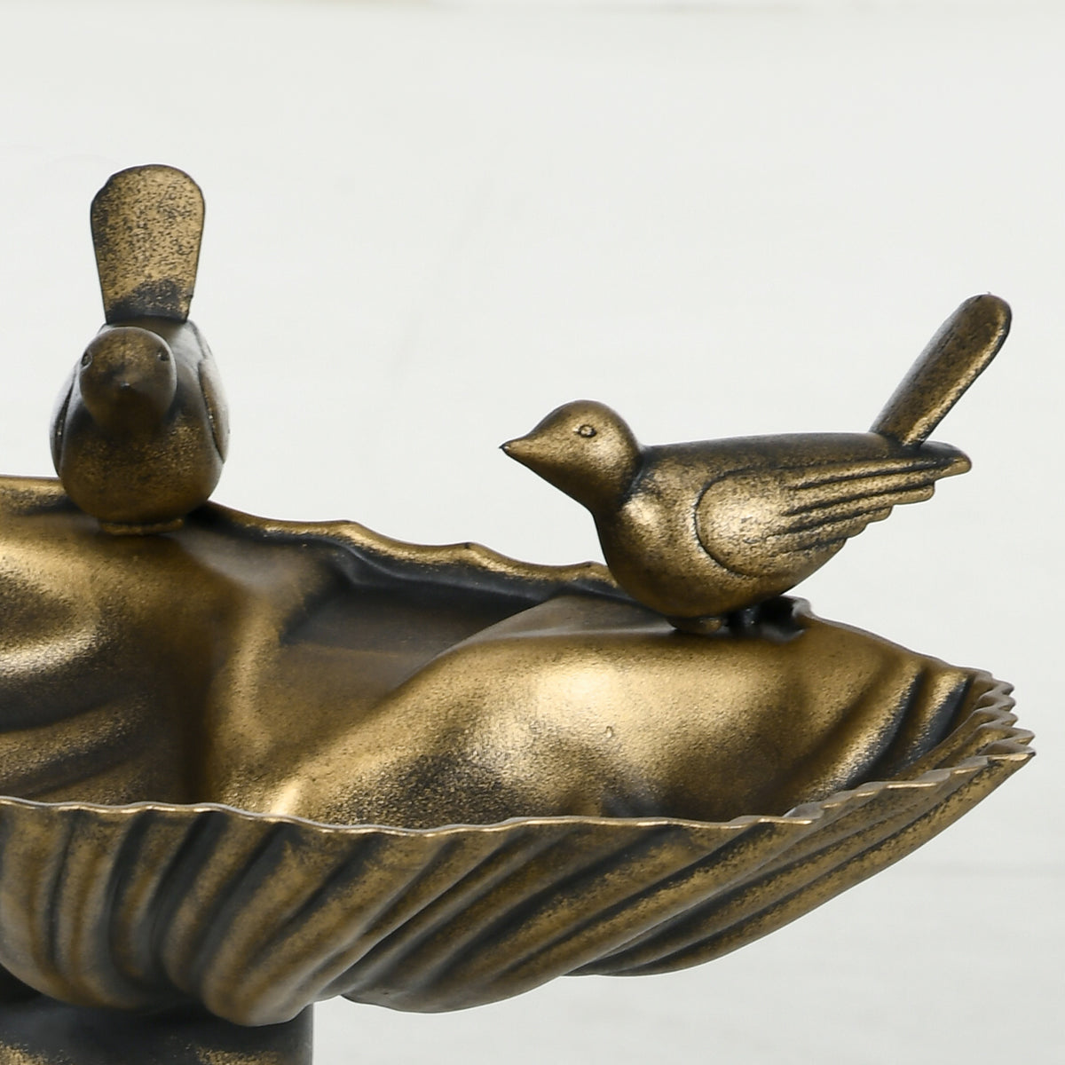 Close-up of the two bronze songbird figurines perched on the shell-shaped bird bath basin