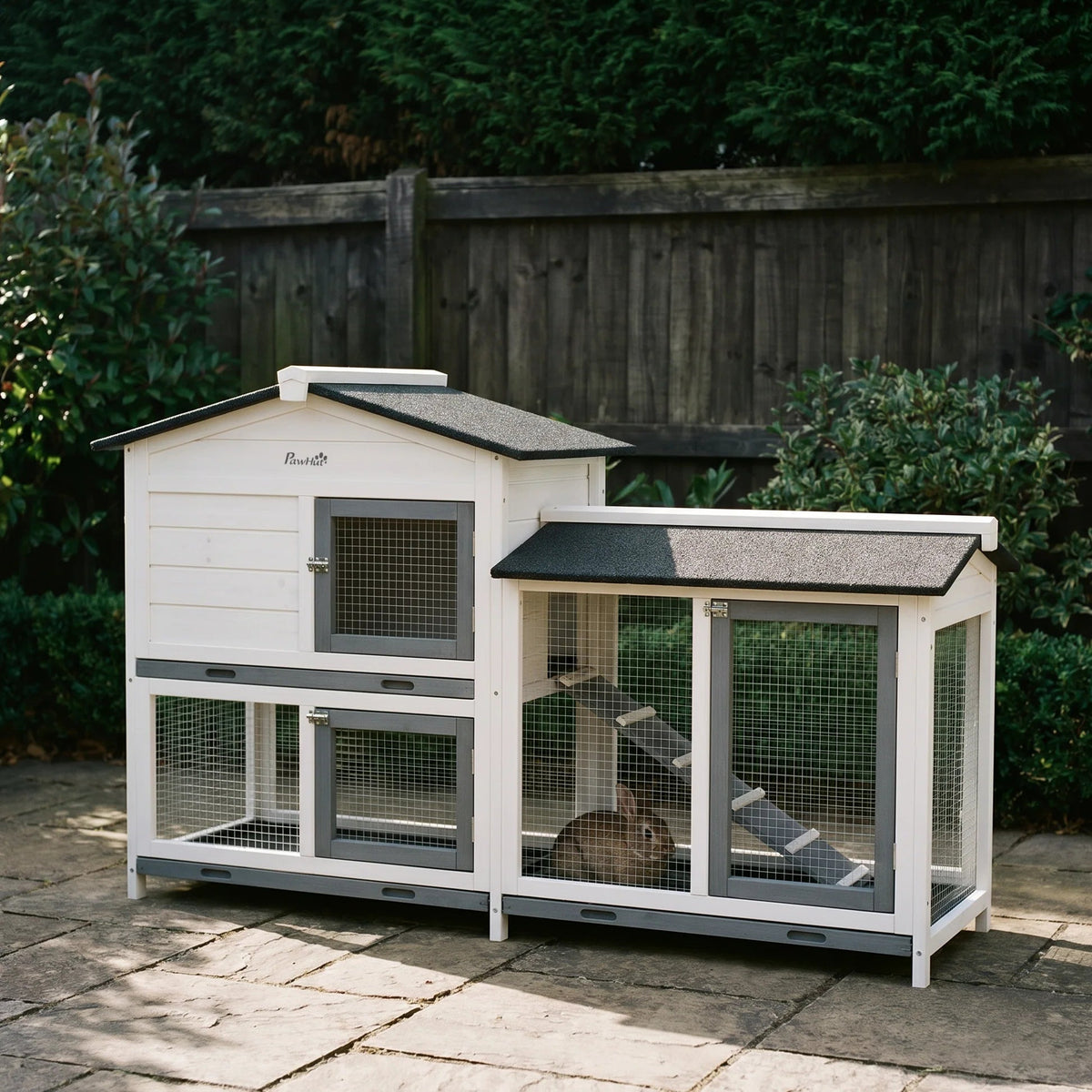 White wooden rabbit hutch with run and ramp on a garden patio - wrenwood hero
