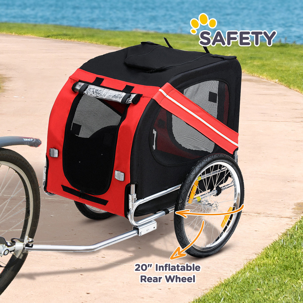 Red and black dog bike trailer hitched behind a bicycle on a lakeside path, with its 20 inch rear wheel