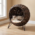 Woven banana-leaf raised cat bed basket in a living room with a cat resting inside - wrenwood hero