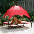 Elevated mesh dog cot with a red canopy shade in a backyard with a dog resting on it - wrenwood hero