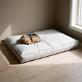 Light grey waterproof pet sofa bed cushion on a wood floor with a small dog asleep on it - wrenwood hero