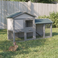 Large grey two-storey wooden rabbit hutch with run in a backyard garden - wrenwood hero