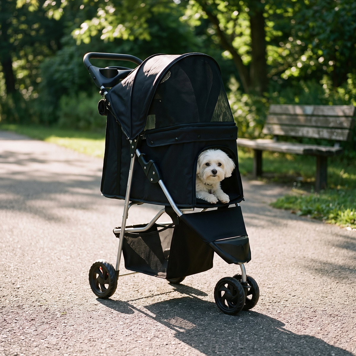 Black three-wheel pet stroller on a park path with a small white dog sitting inside - wrenwood hero