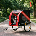 Red and black dog bike trailer on a park path with a dog sitting inside - wrenwood hero