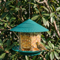 Clear gravity bird feeder with teal roof hanging in a garden - wrenwood hero