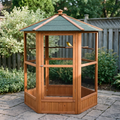 Hexagonal wooden flight bird aviary on a garden patio with a canary perched inside - wrenwood hero