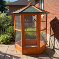 Hexagonal wooden bird aviary on patio pavers with finches - wrenwood ugc lifestyle v2
