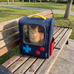 Blue retro console cat backpack sitting on a park bench with an orange tabby looking out - wrenwood ugc lifestyle v2