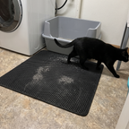 Black cat walking off the honeycomb litter mat beside a high-sided litter box in a laundry room - wrenwood ugc lifestyle v3