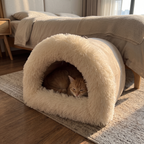 Ginger cat tucked inside the calming cat cave bed on a bedroom floor in morning light