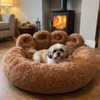 Shih tzu settled in the paw shaped fleece cuddler bed beside a lit wood burner