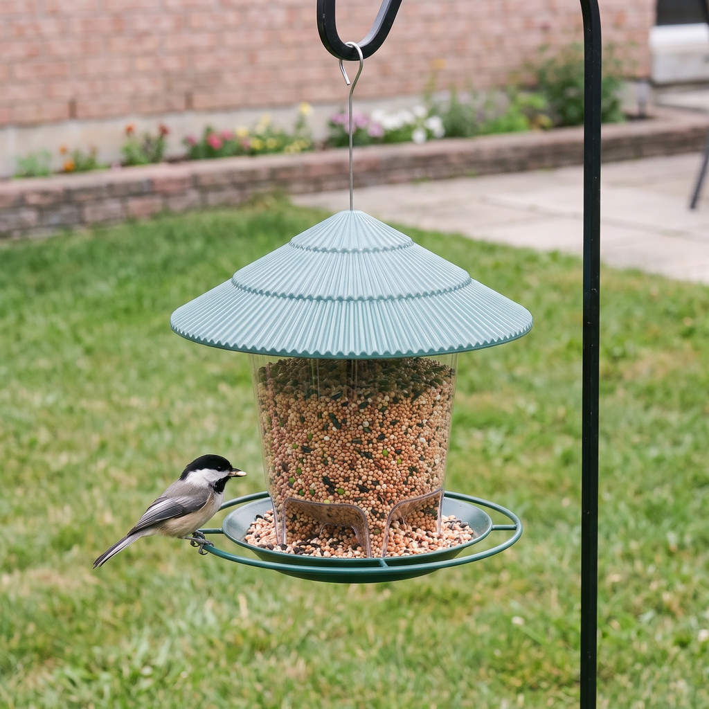 Chickadee feeding at the green-roof hanging metal bird feeder on a garden shepherd's hook