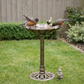 Two robins bathing in the antique resin pedestal bird bath on a tidy back lawn