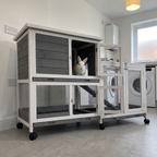 White rabbit in the elevated indoor wooden rabbit hutch with ramp in a tidy utility room